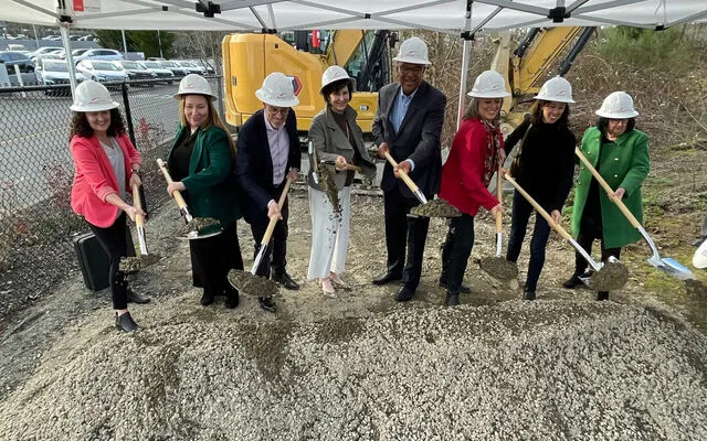 Officials with the City of Bellevue, Amazon, Bridge Housing and King County dig into a pile of dirt with shiny shovels.