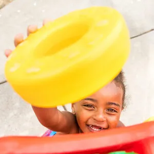 A little boy grins as he reaches up to drop a yellow ring in a giant Connect Four game.