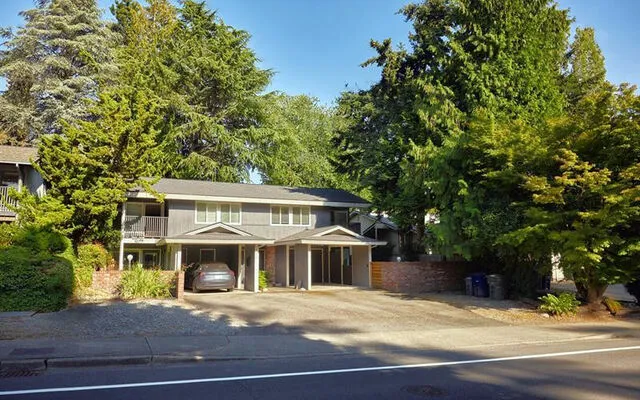 Multifamily housing that looks like a duplex or quadruplex stands between trees on a Bellevue street.