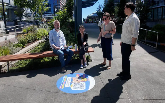 Four people look at a sidewalk decal in downtown Bellevue.