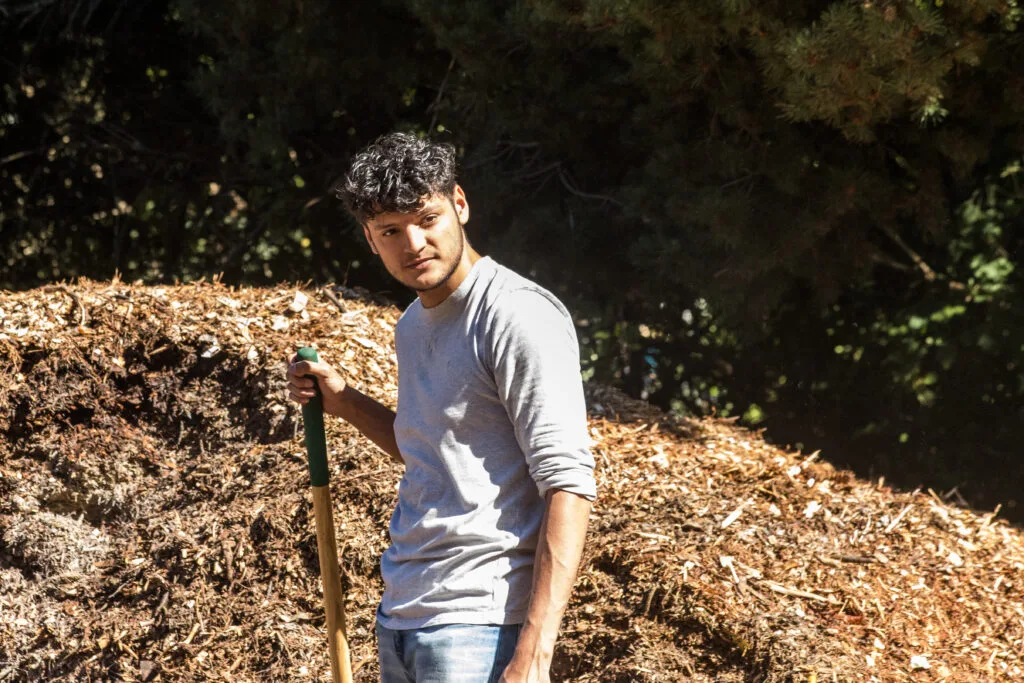 Volunteers shovel mulch from a giant pile into wheelbarrows to cart away.