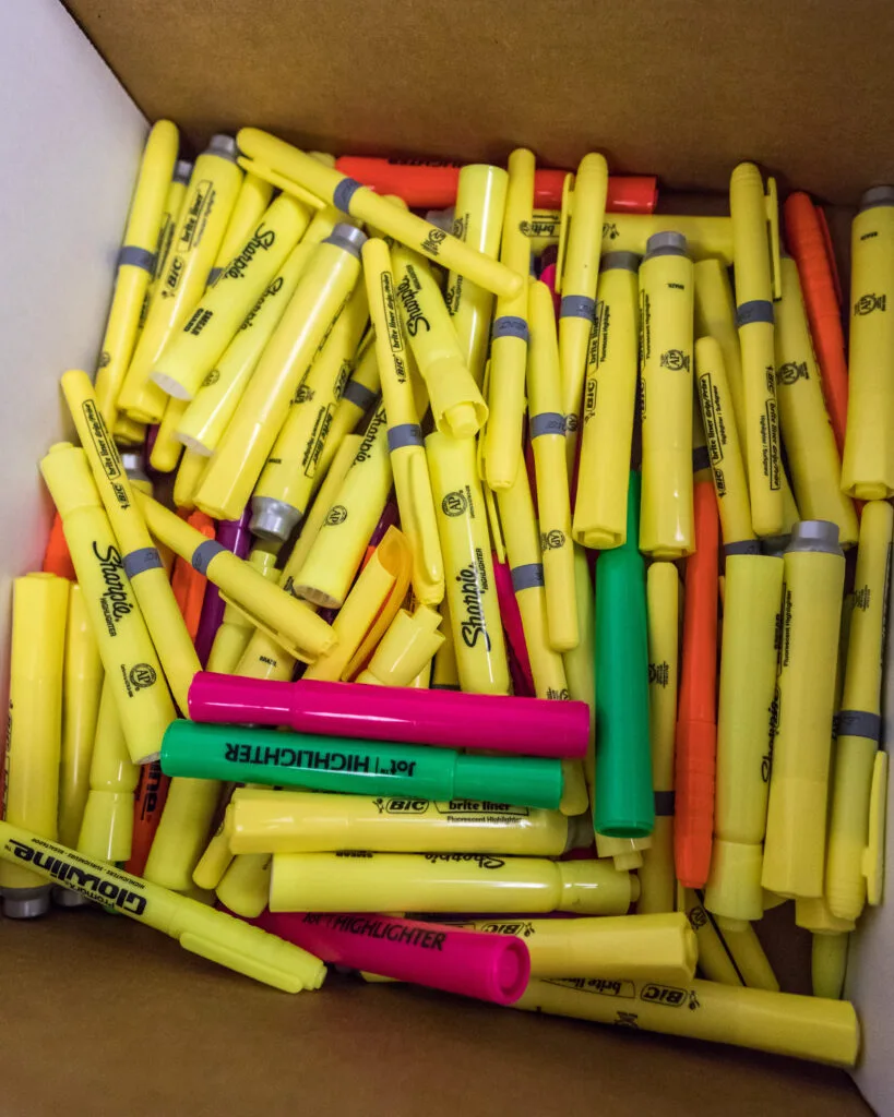 A box full of yellow Sharpie highlighters, with a few pink, green, and orange ones mixed in.