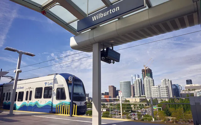 A light rail train arrives at the Wilburton station with downtown in the background.