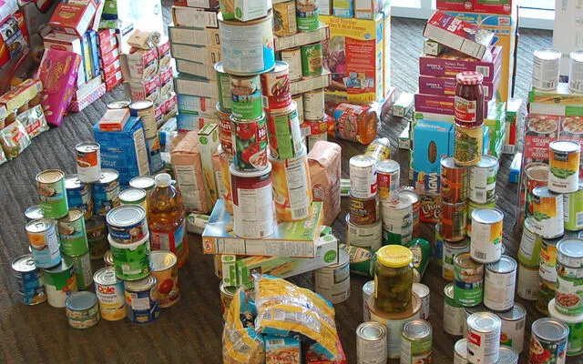 A variety of canned and boxed food is stacked up in a pile.