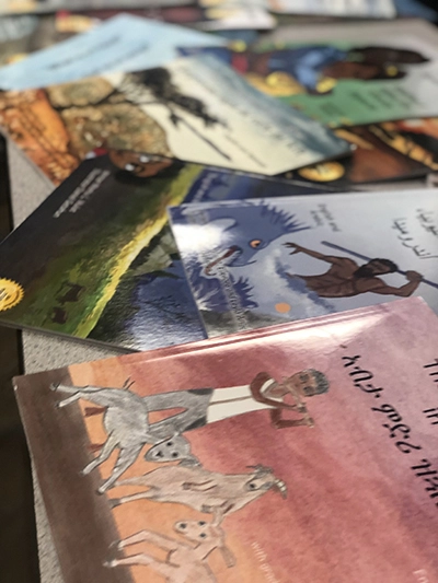 A close up shot of several picture books spread across a table, the visible one in Amharic.