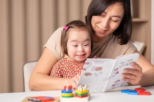 Young child with Down Syndrome smiling looking at a book.
