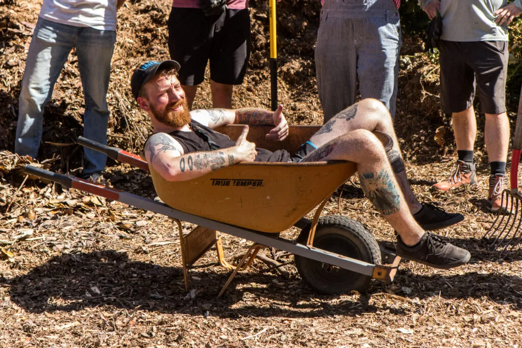 A volunteer relaxes in a wheelbarrow while taking a break from shoveling mulch.