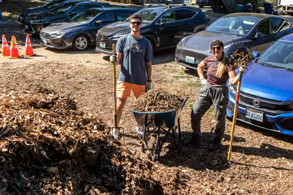A group of volunteers pose by a giant mulch pile.